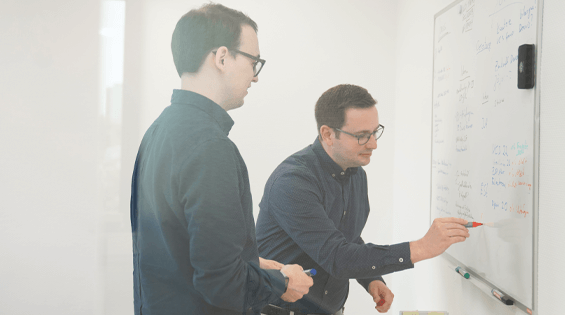 Zwei Mitarbeiter von Löhr schreiben Reporting an ein Whiteboard.