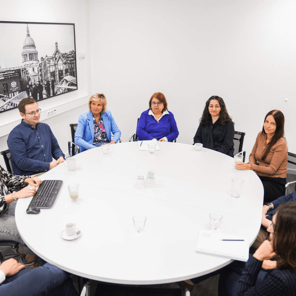 Gruppenfoto: Zehn Teammitglieder von Löhr sitzen um einen runden weißen Tisch und besprechen sich.
