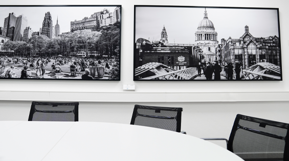 Leerer Meetingraum mit zwei schwarz-weißen Bildern an der Wand, sie zeigen Menschen und Architektur in großen Städten.